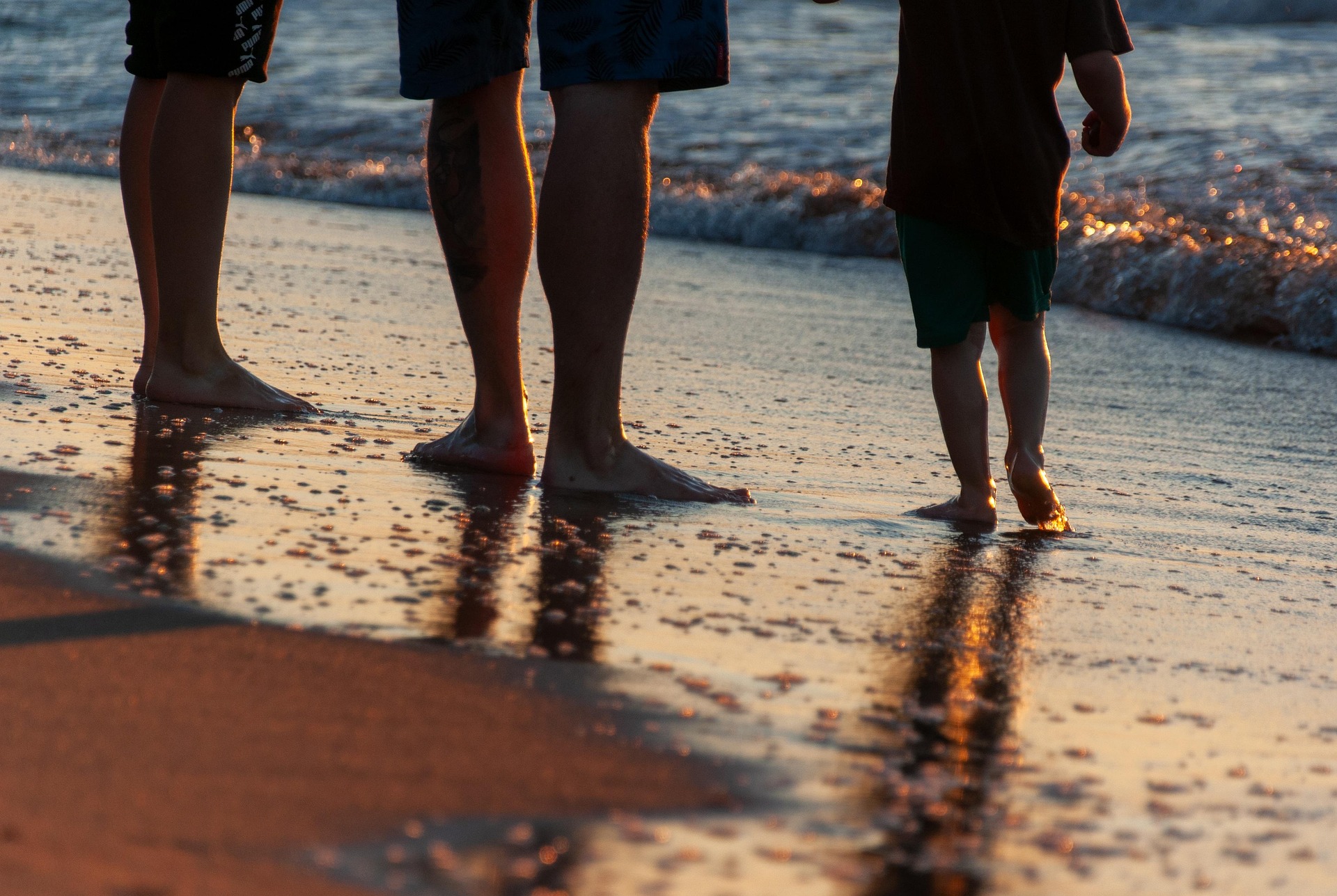 Famille marchant pieds nus sur le sable au bord de l'eau